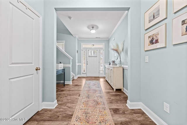 entryway with crown molding, wood finished floors, and baseboards