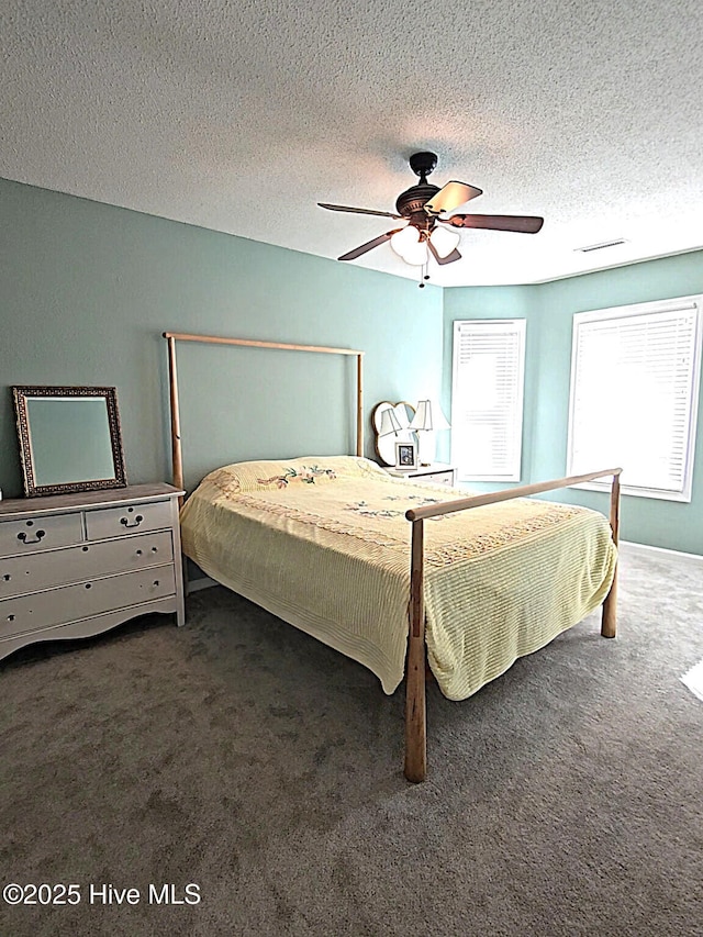 carpeted bedroom with visible vents, a textured ceiling, and a ceiling fan