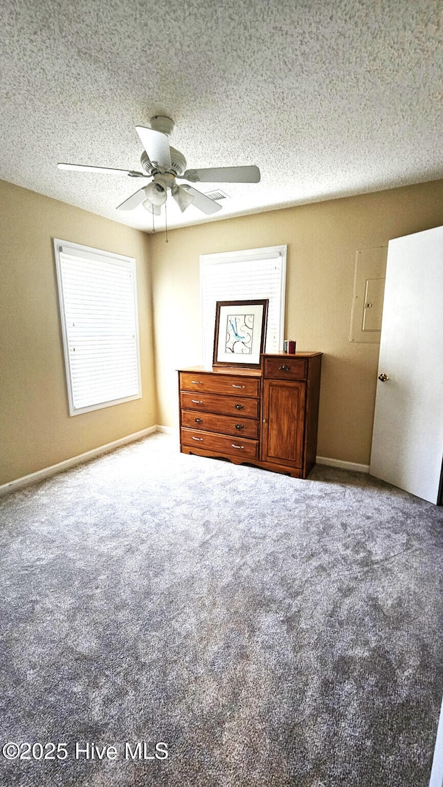 unfurnished bedroom featuring carpet flooring, a textured ceiling, baseboards, and a ceiling fan