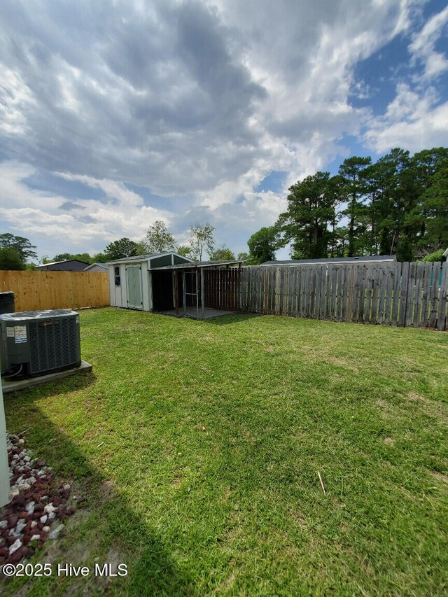 view of yard with an outbuilding, cooling unit, a storage shed, and a fenced backyard