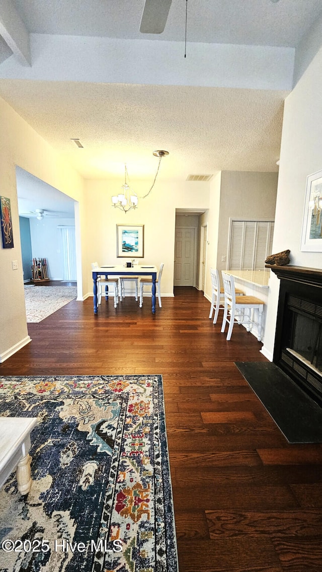 interior space with visible vents, a textured ceiling, wood finished floors, an inviting chandelier, and baseboards