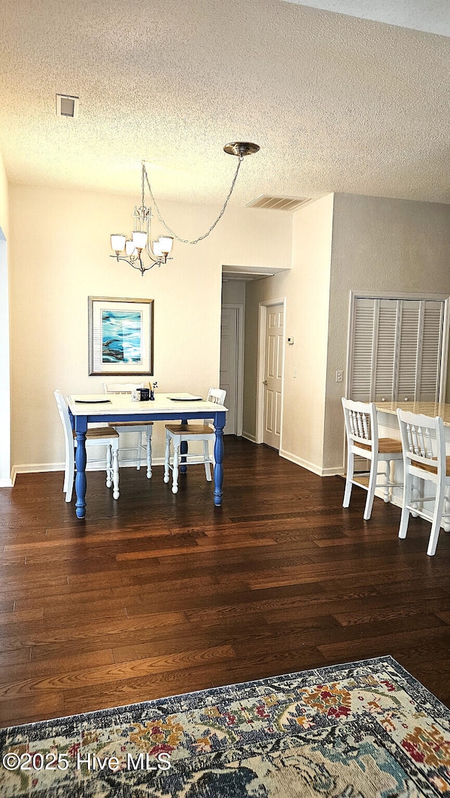 dining area featuring visible vents, a notable chandelier, dark wood finished floors, and a textured ceiling