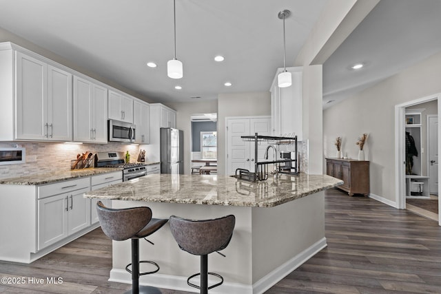 kitchen with dark wood-style floors, white cabinetry, stainless steel appliances, and tasteful backsplash