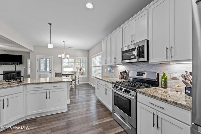 kitchen with a notable chandelier, dark wood-type flooring, backsplash, appliances with stainless steel finishes, and white cabinets