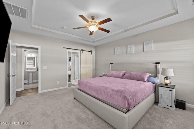 bedroom featuring a barn door, carpet, visible vents, and a tray ceiling