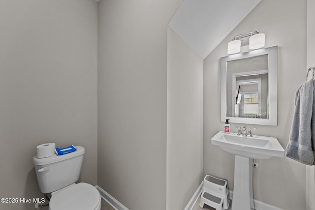 bathroom with vaulted ceiling, toilet, and baseboards