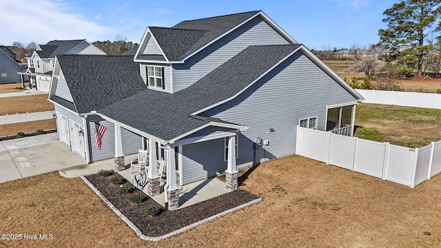 exterior space with a patio, a fenced backyard, a shingled roof, concrete driveway, and a lawn