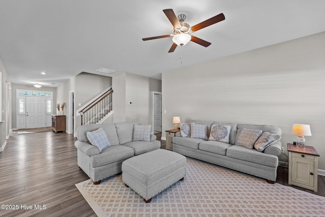 living area with stairway, a ceiling fan, wood finished floors, visible vents, and baseboards