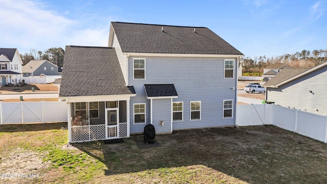 rear view of property featuring a gate, roof with shingles, a yard, a fenced backyard, and a sunroom