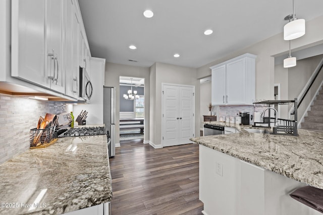 kitchen with white cabinetry, light stone counters, dark wood finished floors, and a sink