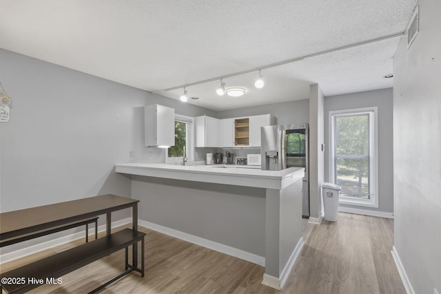 kitchen with a peninsula, light countertops, visible vents, and white cabinets