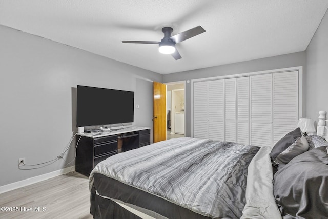 bedroom featuring a closet, light wood-style floors, a textured ceiling, washer / dryer, and baseboards