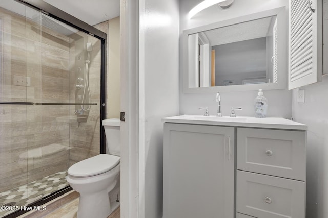 bathroom featuring toilet, a shower stall, wood finished floors, and vanity