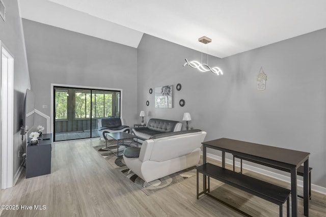 living room featuring wood finished floors, a towering ceiling, and baseboards