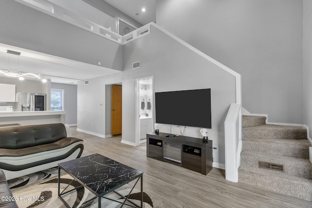 living area with stairs, light wood-type flooring, and visible vents