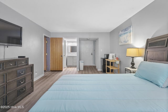 bedroom featuring connected bathroom, baseboards, and wood finished floors