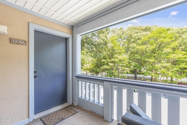 property entrance with a balcony and stucco siding