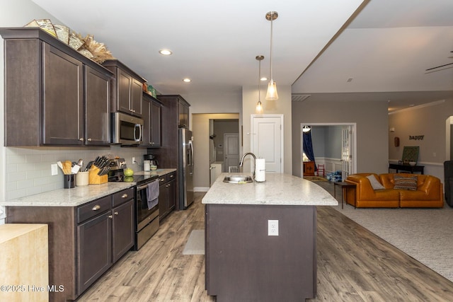 kitchen featuring a sink, open floor plan, dark brown cabinets, appliances with stainless steel finishes, and backsplash