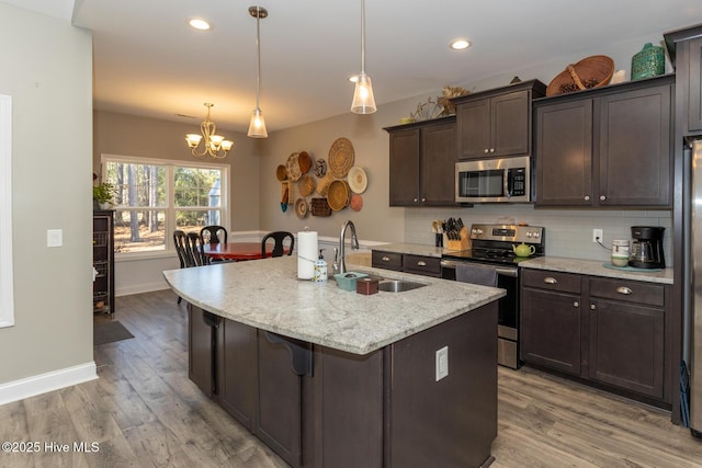 kitchen with tasteful backsplash, light wood-style flooring, stainless steel appliances, dark brown cabinets, and a sink