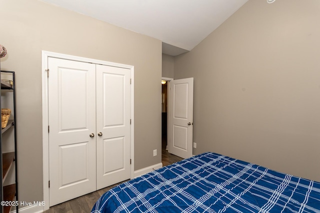 bedroom with dark wood-style floors, baseboards, and a closet