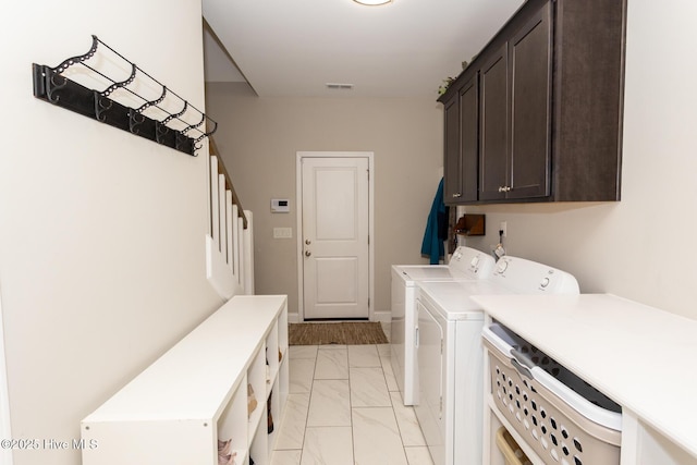 clothes washing area featuring visible vents, marble finish floor, washing machine and clothes dryer, and cabinet space