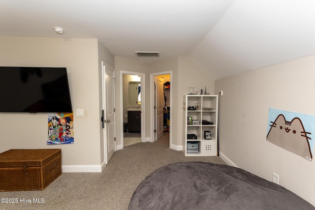 interior space with visible vents, baseboards, carpet, vaulted ceiling, and a walk in closet