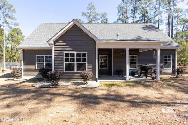 back of house with a shingled roof and a patio area