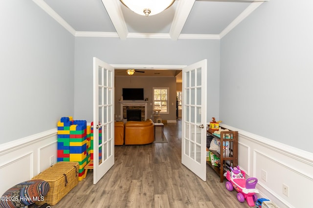 recreation room featuring wainscoting, wood finished floors, beam ceiling, and french doors