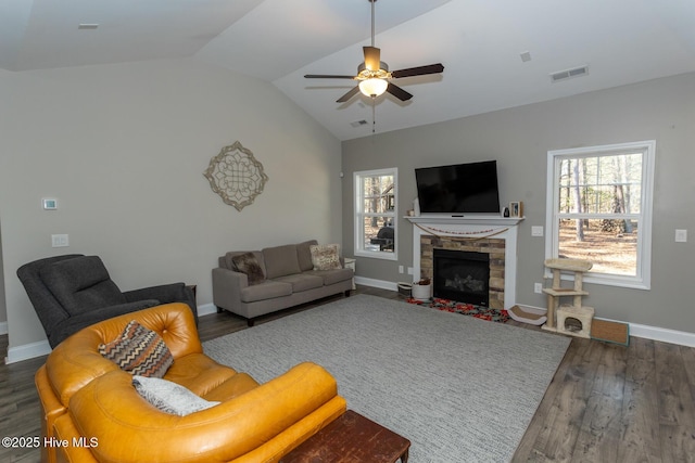 living room with ceiling fan, a fireplace, wood finished floors, baseboards, and vaulted ceiling