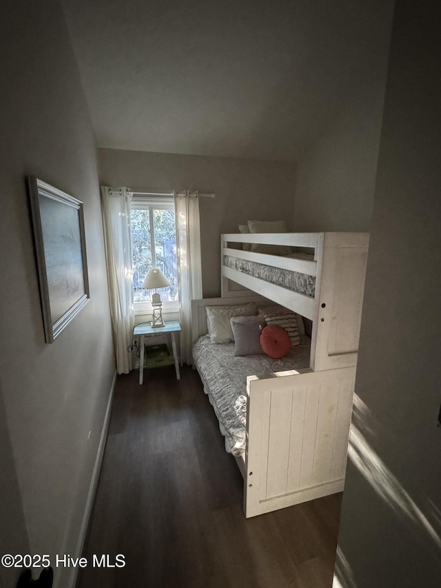 bedroom with vaulted ceiling, baseboards, and dark wood finished floors