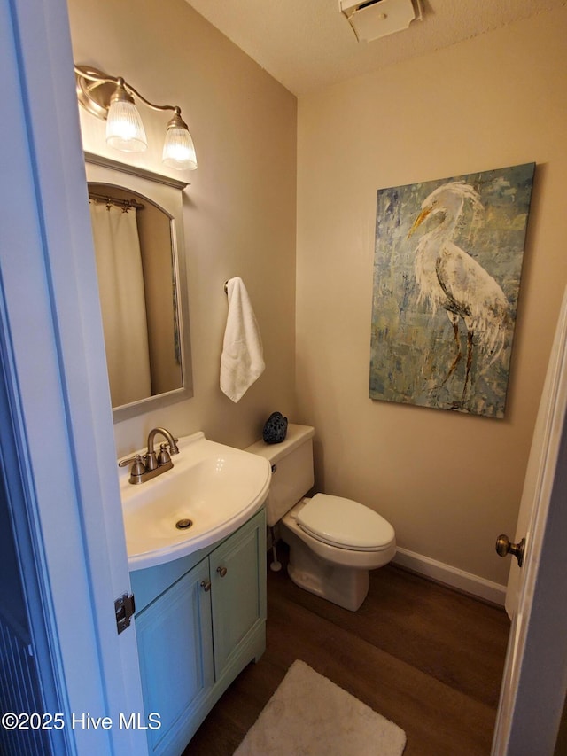 full bath with toilet, wood finished floors, vanity, and baseboards