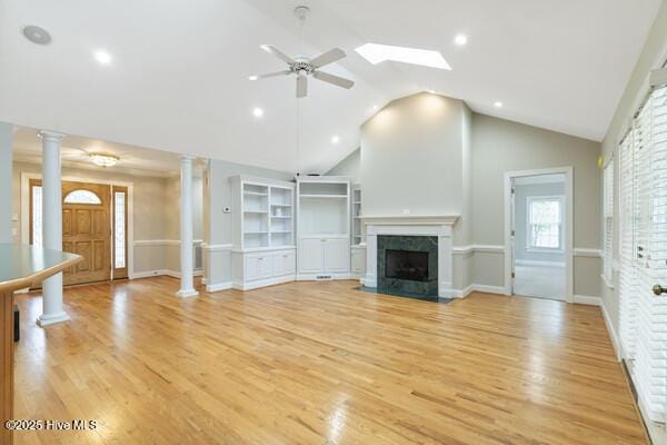 unfurnished living room featuring a premium fireplace, decorative columns, and light wood-style floors