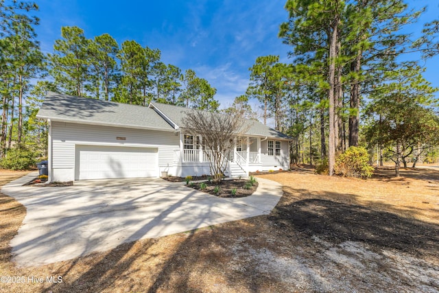 view of front of home with a porch, driveway, a shingled roof, and an attached garage