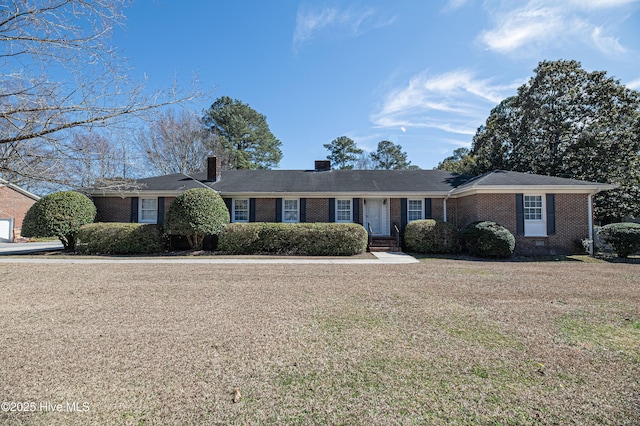 ranch-style home with brick siding, a chimney, and a front lawn