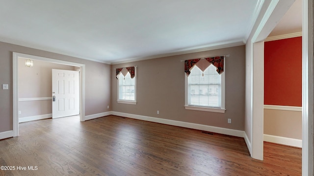 empty room featuring visible vents, crown molding, baseboards, and wood finished floors