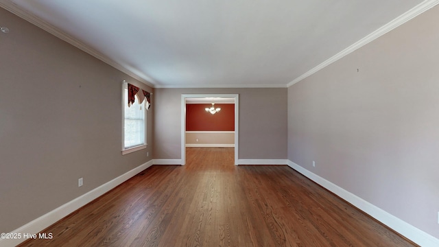 spare room featuring dark wood-type flooring, crown molding, a notable chandelier, and baseboards