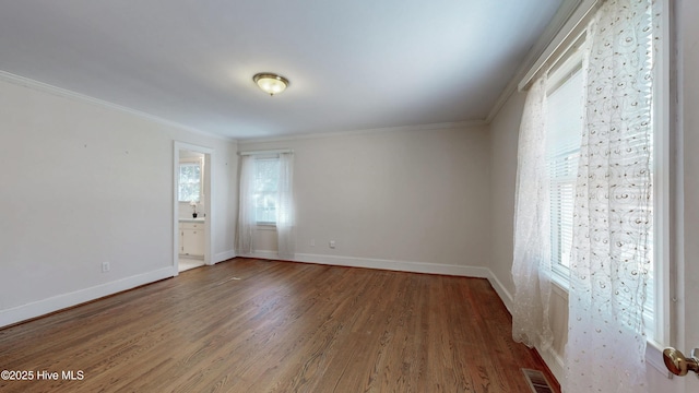 spare room featuring baseboards, crown molding, visible vents, and wood finished floors