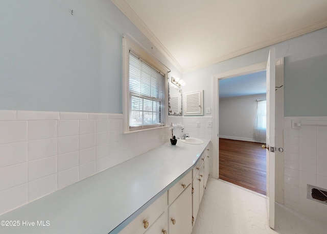 bathroom with a wainscoted wall, crown molding, tile walls, and vanity