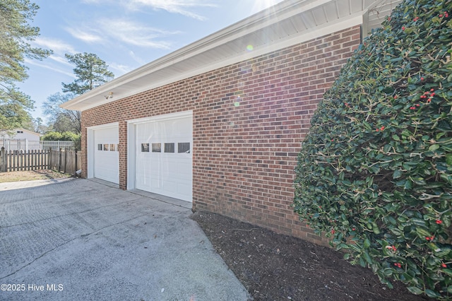 garage featuring concrete driveway and fence