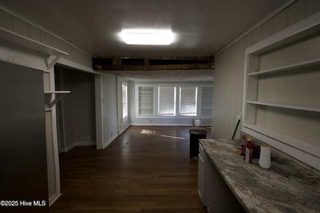 hall with built in shelves, dark wood finished floors, baseboards, and ornamental molding