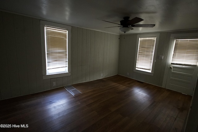 spare room featuring visible vents, a ceiling fan, and dark wood-type flooring