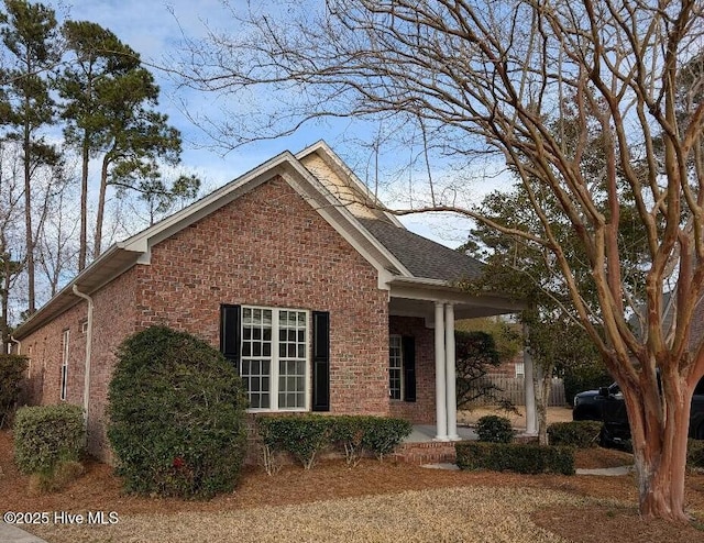 view of side of property featuring brick siding and roof with shingles