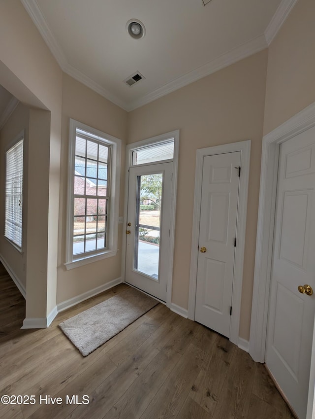 entryway featuring visible vents, crown molding, and wood finished floors