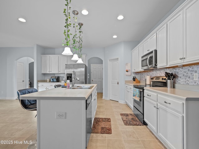 kitchen with arched walkways, stainless steel appliances, light countertops, and a sink