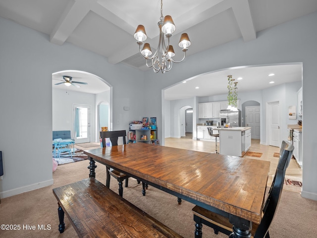 dining space featuring arched walkways, beamed ceiling, and light carpet