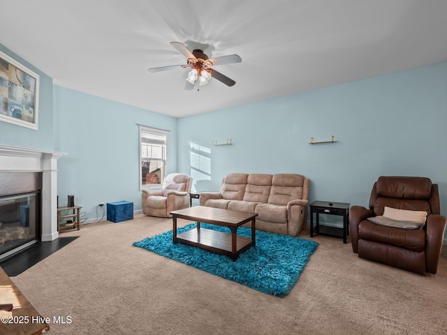 carpeted living room with a fireplace with flush hearth, baseboards, and a ceiling fan