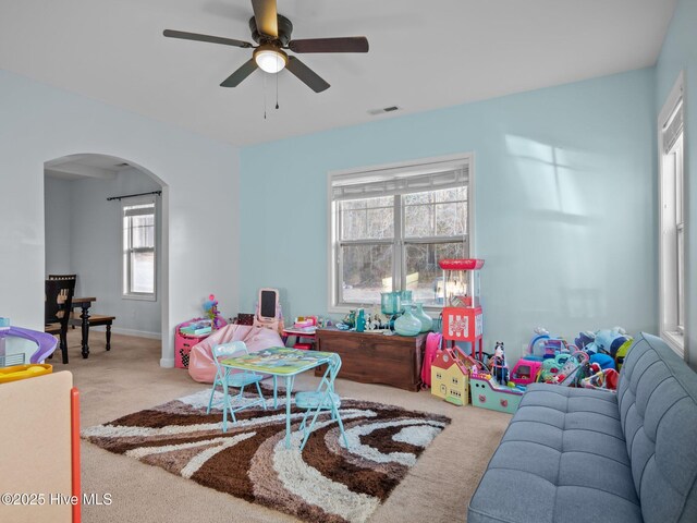 living area featuring visible vents, arched walkways, carpet floors, and ceiling fan