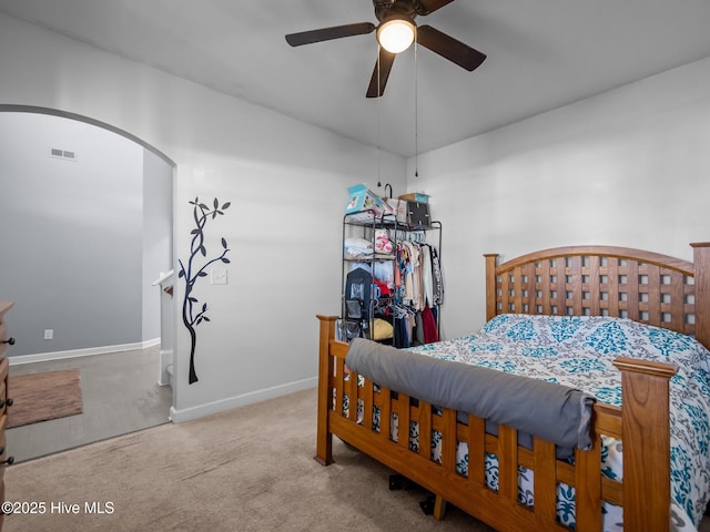 carpeted bedroom with arched walkways, visible vents, ceiling fan, and baseboards