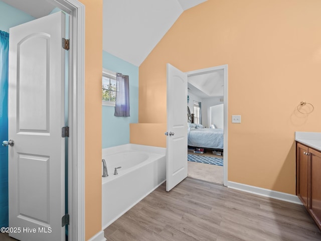 full bathroom featuring vanity, a garden tub, lofted ceiling, wood finished floors, and ensuite bath