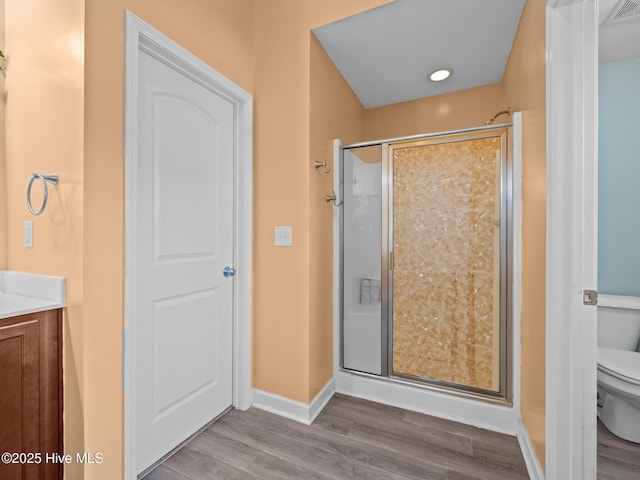 full bath with a shower stall, toilet, baseboards, and wood finished floors